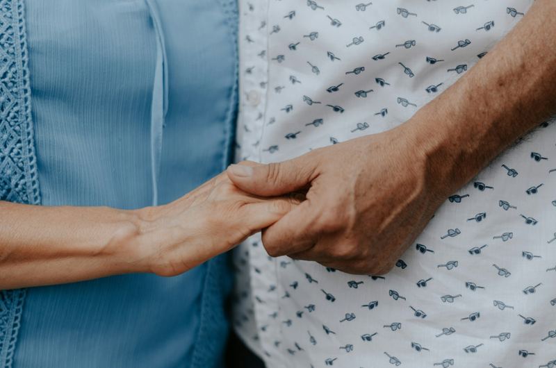 A caregiver holding an older person's hand in both of theirs