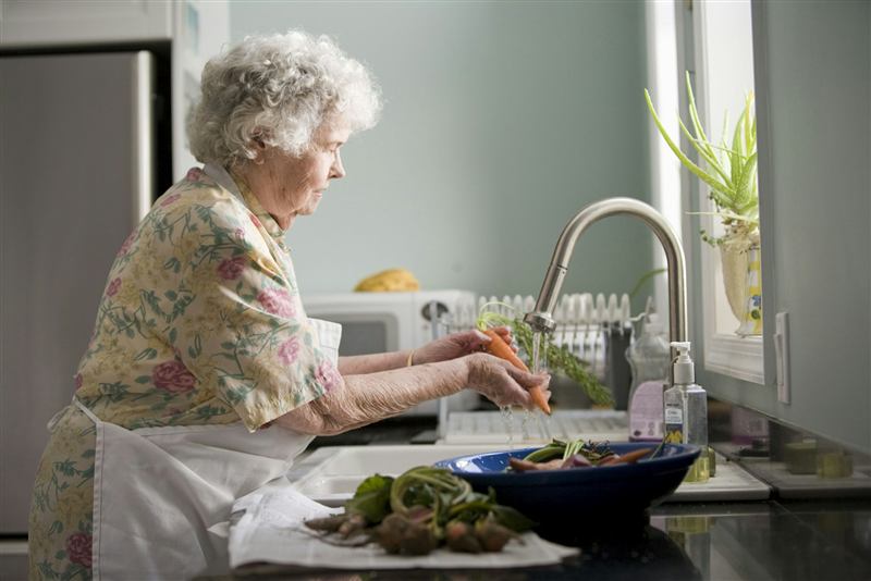 Fresh vegetables being washed in a sunlit kitchen